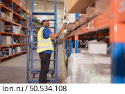Male clerk using digital tablet while standing on stairs in warehouse to inspect goods. Стоковое фото, агентство Ingram Publishing / Фотобанк Лори