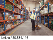 Warehouse workers pushing a pallet truck in a shipping and distribution warehouse. Стоковое фото, агентство Ingram Publishing / Фотобанк Лори