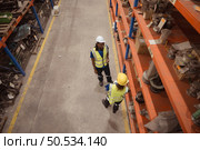 High angle view of warehouse workers in hardhats lifting boxes at warehouse. Стоковое фото, агентство Ingram Publishing / Фотобанк Лори