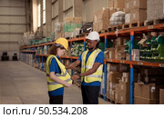 The male supervisor helps to look at the dress of the female staff before entering the warehouse. for the safety of inspection work in the warehouse. Стоковое фото, агентство Ingram Publishing / Фотобанк Лори