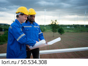 Back view of engineer and technician looking at wind turbines in the field before go in and check wind turbine, The concept of natural energy from wind. Стоковое фото, агентство Ingram Publishing / Фотобанк Лори