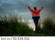 Young woman in engineer uniform and high visibility with raised arms standing on grassy field at sunset, The concept of relax time after work. Стоковое фото, агентство Ingram Publishing / Фотобанк Лори