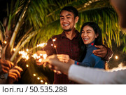 Portrait of Happy Asian group of friends having fun with sparklers outdoor - Young people having fun with fireworks at night time  - People, food, drink lifestyle, new year celebration concept. Стоковое фото, агентство Ingram Publishing / Фотобанк Лори