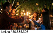 Portrait of Happy Asian group of friends having fun with sparklers outdoor - Young people having fun with fireworks at night time  - People, food, drink lifestyle, new year celebration concept. Стоковое фото, агентство Ingram Publishing / Фотобанк Лори