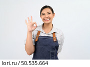 Portrait Asian young woman in waitress uniform and apron showing finger OK sign posture, Pretty woman with body language for feel good isolated on white background, copy space. Стоковое фото, агентство Ingram Publishing / Фотобанк Лори