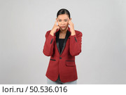 Portrait of young asian woman in officer uniform with headache posture, she raise two hand and use finger touch on face with stressful with tired work, isolated on white background. Стоковое фото, агентство Ingram Publishing / Фотобанк Лори