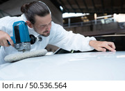 Auto mechanic use an electric polisher to polish the dried car paint. After passing the paint from the car painting room. Стоковое фото, агентство Ingram Publishing / Фотобанк Лори