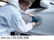 Auto mechanic use an electric polisher to polish the dried car paint. After passing the paint from the car painting room. Стоковое фото, агентство Ingram Publishing / Фотобанк Лори