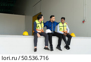 A warehouse manager and two employees are resting after dealing with how to organize the shelves in a large warehouse. Стоковое фото, агентство Ingram Publishing / Фотобанк Лори