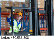 Worker in auto parts warehouse use a forklift to work to bring the box of auto parts into the storage shelf of the warehouse waiting for delivery to the car assembly line. Стоковое фото, агентство Ingram Publishing / Фотобанк Лори