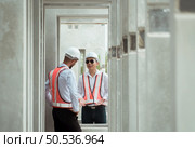 Both of construction engineers verify the constructed precast concrete wall slabs’ quality. also to oversee significant construction projects in the construction zone. Стоковое фото, агентство Ingram Publishing / Фотобанк Лори