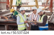 Group of architects, construction foremen, and construction engineers review the work and talk about how the project, in the construction site. Стоковое фото, агентство Ingram Publishing / Фотобанк Лори