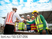Construction engineers, architects, and foremen form a group. Participate in a meeting to plan new construction projects. Cheers to express happiness that the event was successfully accomplished. Стоковое фото, агентство Ingram Publishing / Фотобанк Лори