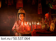 Chinese woman make wishes, pray, and light candles. On the occasion of the annual Chinese New Year festival, in a revered shrine or temple, And in Chinese where candles mean good luck and happiness. Стоковое фото, агентство Ingram Publishing / Фотобанк Лори