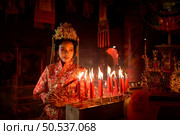 Chinese woman make wishes, pray, and light candles. On the occasion of the annual Chinese New Year festival, in a revered shrine or temple, And in Chinese where candles mean good luck and happiness. Стоковое фото, агентство Ingram Publishing / Фотобанк Лори
