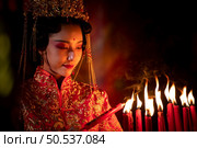 Chinese woman make wishes, pray, and light candles. On the occasion of the annual Chinese New Year festival, in a revered shrine or temple, And in Chinese where candles mean good luck and happiness. Стоковое фото, агентство Ingram Publishing / Фотобанк Лори