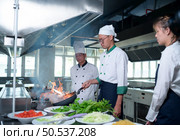 Young chef, University professor is passing on the knowledge of cooking to students. Стоковое фото, агентство Ingram Publishing / Фотобанк Лори