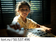 Portrait of a little girl in office room of house with a game of Go being learned to build concentration and intelligence. Стоковое фото, агентство Ingram Publishing / Фотобанк Лори