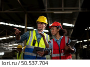 The foreign chief engineer came to inspect the old mechanical factory. There is an African female mechanic explaining details and progress reports on old machines being repaired to restore normal operation. Стоковое фото, агентство Ingram Publishing / Фотобанк Лори