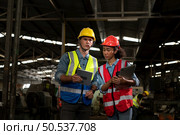 The foreign chief engineer came to inspect the old mechanical factory. There is an African female mechanic explaining details and progress reports on old machines being repaired to restore normal operation. Стоковое фото, агентство Ingram Publishing / Фотобанк Лори