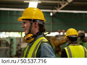 Chief mechanical engineer working in a mechanical factory make radio communication control with walkie-talkie and follow up with Asian technicians who are repairing old machines. Стоковое фото, агентство Ingram Publishing / Фотобанк Лори