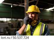 Chief mechanical engineer working in a mechanical factory make radio communication control with walkie-talkie and follow up with Asian technicians who are repairing old machines. Стоковое фото, агентство Ingram Publishing / Фотобанк Лори