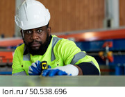Young engineers engineers testing and confirming that the machinery at the factory that creates metal sheet tiles is functioning as intended. Стоковое фото, агентство Ingram Publishing / Фотобанк Лори