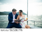 On a yacht, a businessman begins his family’s vacation. a huge project agreement was successfully closed, which was wonderful news. Стоковое фото, агентство Ingram Publishing / Фотобанк Лори