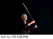 Senior Japanese samurai with katana sword on black background, studio shot. Стоковое фото, агентство Ingram Publishing / Фотобанк Лори