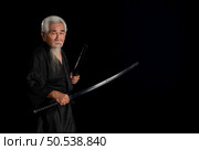 Senior Japanese samurai with katana sword on black background, studio shot. Стоковое фото, агентство Ingram Publishing / Фотобанк Лори