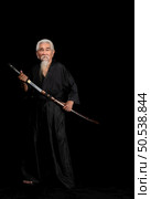 Senior Japanese samurai with katana sword on black background, studio shot. Стоковое фото, агентство Ingram Publishing / Фотобанк Лори