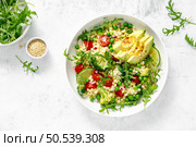 Couscous salad with broccoli, green peas, tomatoes, avocado and fresh arugula. Healthy natural plant based vegetarian food for lunch, israeli cuisine, top view. Стоковое фото, агентство Ingram Publishing / Фотобанк Лори