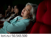 Senior woman falls asleep while watching movie in cinema and popcorn in hand, Movie lacking interesting and boring. Стоковое фото, агентство Ingram Publishing / Фотобанк Лори