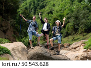 Young man hiker with backpack and trekking poles with a young man helping to pull him up to stand on the rock. Стоковое фото, агентство Ingram Publishing / Фотобанк Лори