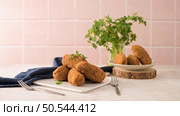Cod dumplings, or "bolinhos de bacalhau" and parsley leaves on white ceramic dishes in a kitchen counter top. Стоковое фото, агентство Ingram Publishing / Фотобанк Лори