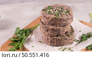 Raw veggie burger with black beans with parsley leaves on wood cutting board. Стоковое фото, агентство Ingram Publishing / Фотобанк Лори