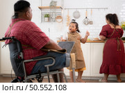 A plus-size family with a father wearing a prosthetic leg, They happily make breakfast together in the in the kitchen room of the house. Стоковое фото, агентство Ingram Publishing / Фотобанк Лори