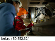 Two engineers for electric trains After detecting difficulties with the electric train’s machinery use searchlights to locate and check damaged sections. In the electric train repair shop. Стоковое фото, агентство Ingram Publishing / Фотобанк Лори