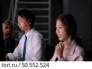 Group of broker international stock traders wearing headset working actively at night in office, Concept of customer support agent provide service on telephone. Стоковое фото, агентство Ingram Publishing / Фотобанк Лори