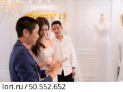 Bridal gown designers and tailors measure the size of the gown against the bride’s figure when she comes to try on the gown in order to make it perfect and ready to wear on the wedding day. Стоковое фото, агентство Ingram Publishing / Фотобанк Лори