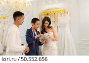 Bridal gown designers and tailors measure the size of the gown against the bride’s figure when she comes to try on the gown in order to make it perfect and ready to wear on the wedding day. Стоковое фото, агентство Ingram Publishing / Фотобанк Лори