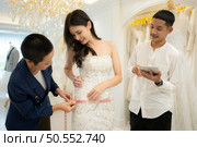 Bridal gown designers and tailors measure the size of the gown against the bride’s figure when she comes to try on the gown in order to make it perfect and ready to wear on the wedding day. Стоковое фото, агентство Ingram Publishing / Фотобанк Лори