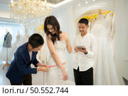 Bridal gown designers and tailors measure the size of the gown against the bride’s figure when she comes to try on the gown in order to make it perfect and ready to wear on the wedding day. Стоковое фото, агентство Ingram Publishing / Фотобанк Лори