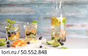 Summer healthy cocktails of citrus infused waters, lemonades or mojitos, with lime lemon orange blueberries and mint, diet detox beverages, in glasses on light background. Стоковое фото, агентство Ingram Publishing / Фотобанк Лори