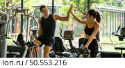 Young couples work out at the gym to strengthen the body. Each person recommends exercise for each other and encourage each other while exercising. Стоковое фото, агентство Ingram Publishing / Фотобанк Лори