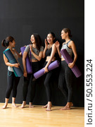 Yoga class of young people interested in yoga activities With a yoga teacher who helps teach yoga postures to students In order to be physically strong and flexible. Стоковое фото, агентство Ingram Publishing / Фотобанк Лори