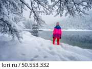 Young woman in red in beautiful snowy forest near lake in winter. Kranjska Gora, Slovenia. Landscape with trees in snow, sporty girl, trail. Snowfall in foggy woods. Wintry woodland. Trees in hoar. Young woman in red in beautiful snowy forest near lake in winter. Стоковое фото, агентство Ingram Publishing / Фотобанк Лори
