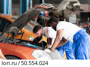 Car mechanic working in an auto repair shop, inspecting the operation of the car’s air conditioner and refrigerant. Стоковое фото, агентство Ingram Publishing / Фотобанк Лори