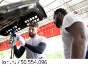 Car mechanic working in an auto repair shop, inspecting the operation of the car’s air conditioner and refrigerant. Стоковое фото, агентство Ingram Publishing / Фотобанк Лори