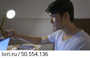 When the laptop was turned on, a young Asian man working overtime at home received good news regarding the project he worked on. Стоковое фото, агентство Ingram Publishing / Фотобанк Лори